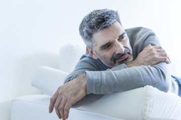 Relaxed mature man at home lying on couch