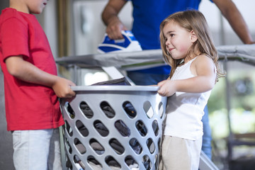 Two children helping father with chores carrying laundry basket