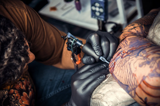 Tattoo specialist showing process of making a tattoo in tattoo studio