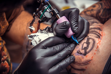 Fototapeta na wymiar Professional tattoo artist showing process of making a tattoo in tattoo parlor