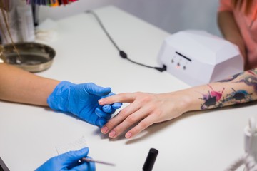 Fototapeta na wymiar Manicurist master makes manicure on young woman hand