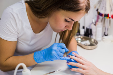 Nails painting with brush in nail salon on woman hands