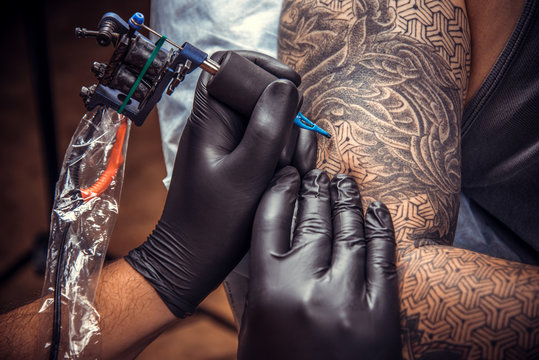Professional tattooer works in tattoo parlor