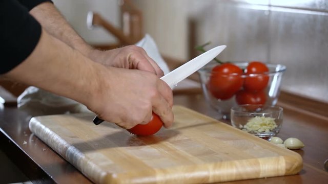 man cuts a tomato for cooking bruschetta