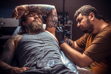 Professional tattooer create tattoo in tattoo studio