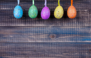 Colorful Easter eggs are suspended on the backdrop of boards. Easter background. Space for text below.