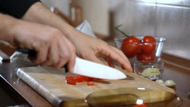 man cuts a tomato for cooking bruschetta