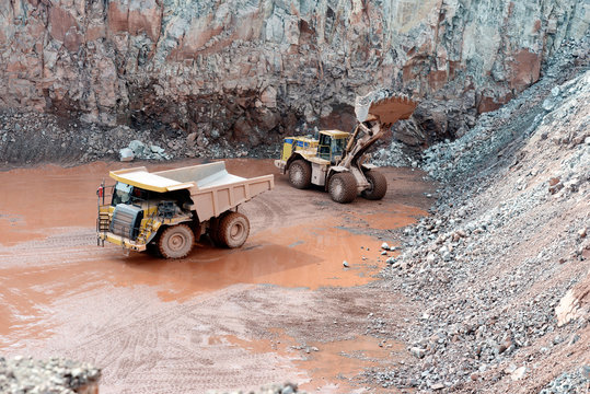 quarry mine of porphyry rock. earthmover loading a dumper truck