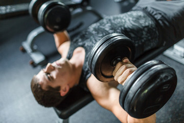 High angle view portrait of muscular man doing bench press exercise for chest muscles using heavy...