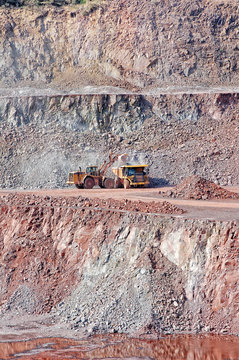 quarry mine of porphyry rock. earthmover loading a dumper truck