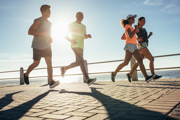 Young people running along seaside