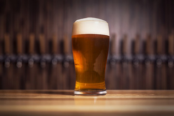 Cleer beer in mug stands on the bar against the background of the taps
