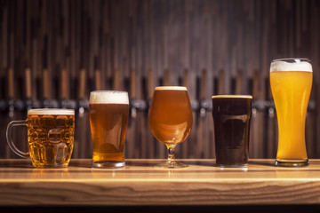 Several different beers are standing in a row at the bar  - obrazy, fototapety, plakaty