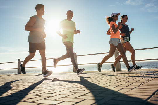 Young people running along seaside