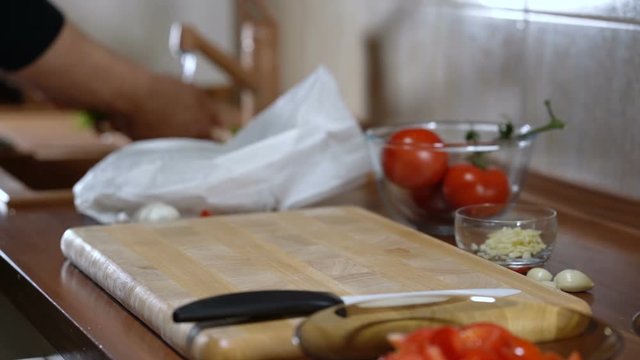 Cutting board with knife and man washes parsley for cooking bruschetta