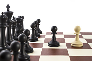 Chess business concept, leader & success. White pawn is challenging black pawn in front of black figures on chess board