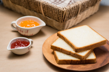 Toast with strawberry and orange jam on a plate on table.