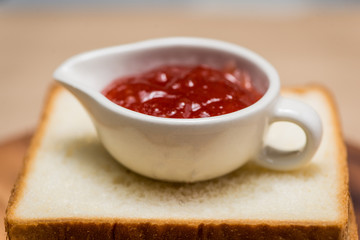 Toast with strawberry jam on a plate on table.