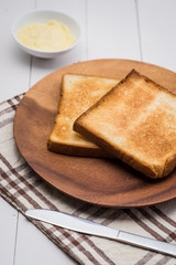 Close-up of slice of toast bread with butter on wood table