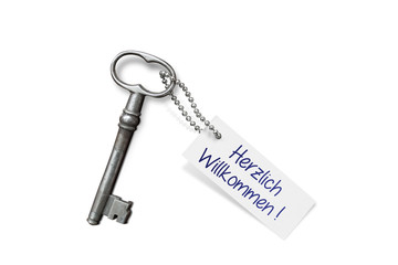 Antiker Schlüssel mit "Herzlich Willkommen" Anhänger freistehend auf weißem Hintergrund