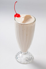 milk cocktail with a cherry in a tall glass