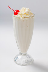 milk cocktail with a cherry in a tall glass