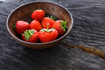 Red fresh strawberries on black rustic wood background