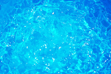 Blue pool water with sun reflections.Shining blue water ripple background.