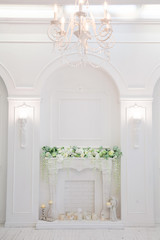 classic design appartments with a white fireplace decorated spring flower, retro chandelier and lamps caryatid. Vertical