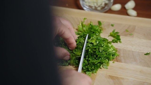 man cuts parsley for cooking bruschetta