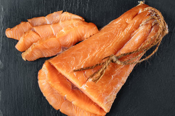 Smoked salmon fish on a slate board. Top view at cutted slices of smoked salmon
