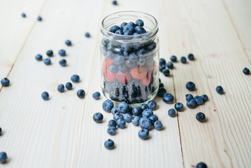 Fototapeta na wymiar Rustic healthy breakfast with blueberry and strawberry in a glass on a wooden table. Glass of ripe berries. Healthy breakfast with vital vitamins.