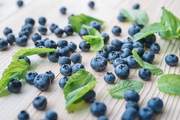 Macro photo of blueberries on a wooden table. Mint leaves with blackberries. Healthy breakfast with vital vitamins.