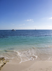 Fototapeta na wymiar Beach view on the Caribbean sea shore. Sunny day for vacation. White sand. Calm ocean.