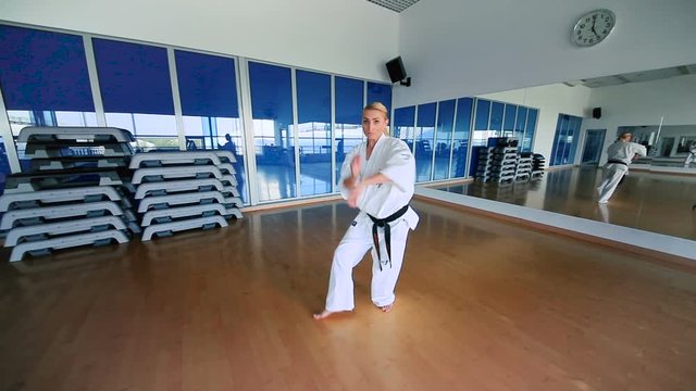 Sporty girl in kimono practicing the karate in the gym
