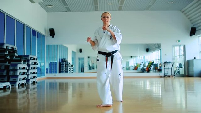 Girl in kimono with black belt show some karate tricks