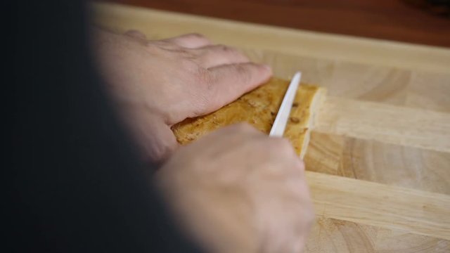 A man cuts bread for cooking bruschetta