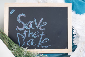 SAVE THE DATE written with chalk on wooden mini blackboard labels