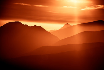 Obraz premium A beautiful, colorful, abstract mountain landscape with sun in a red tonality. Decorative, artistic look.