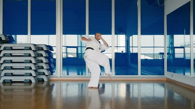 Sporty woman in white kimono practicing the karate tricks in the gym