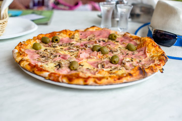 Pizza Capriciosa on white tablecloth closeup shot 