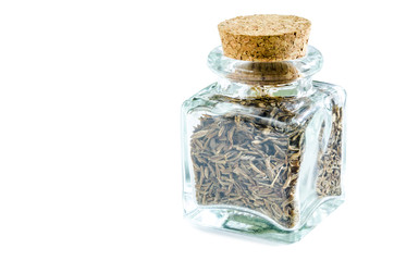 Dry cumin in glass bottle isolated on white background. Closeup macro shot.