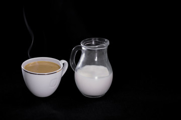 coffee in a white Cup milk in a small jug on black background.