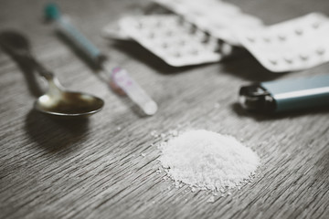 heroin on the table closeup. in the background, syringe, spoon and lighter for dosage preparation....