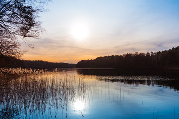 Obraz premium Zachód słońca nad spokojnym wiejskim jeziorem