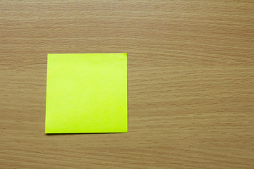 Blank yellow note paper attach on brown wooden background for memo or remind