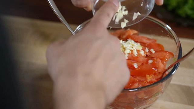 Man mixes ingredients for cooking bruschetta