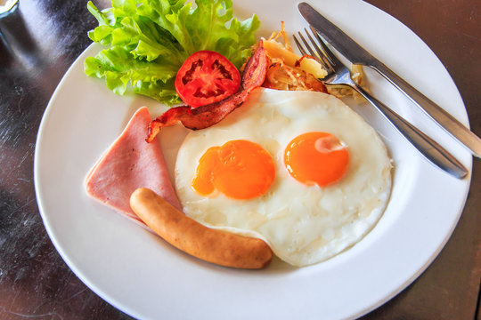 American breakfast; Fried eggs, sausages, ham and fresh salad