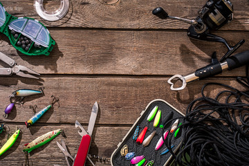 Fishing tackle - fishing spinning, fishing line, hooks and lures on wooden background.