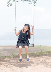 cute girl smile and sit on swing seat.